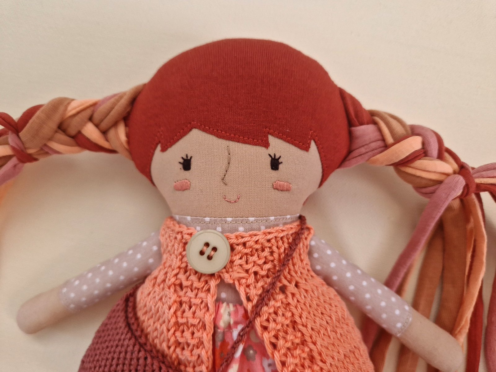 Fabric play doll inside an open fabric bag with interchangeable clothes and accessories.