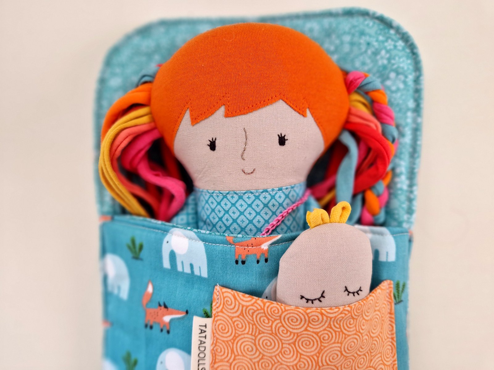Cloth play doll with long hair and interchangeable clothes arranged beside her.
