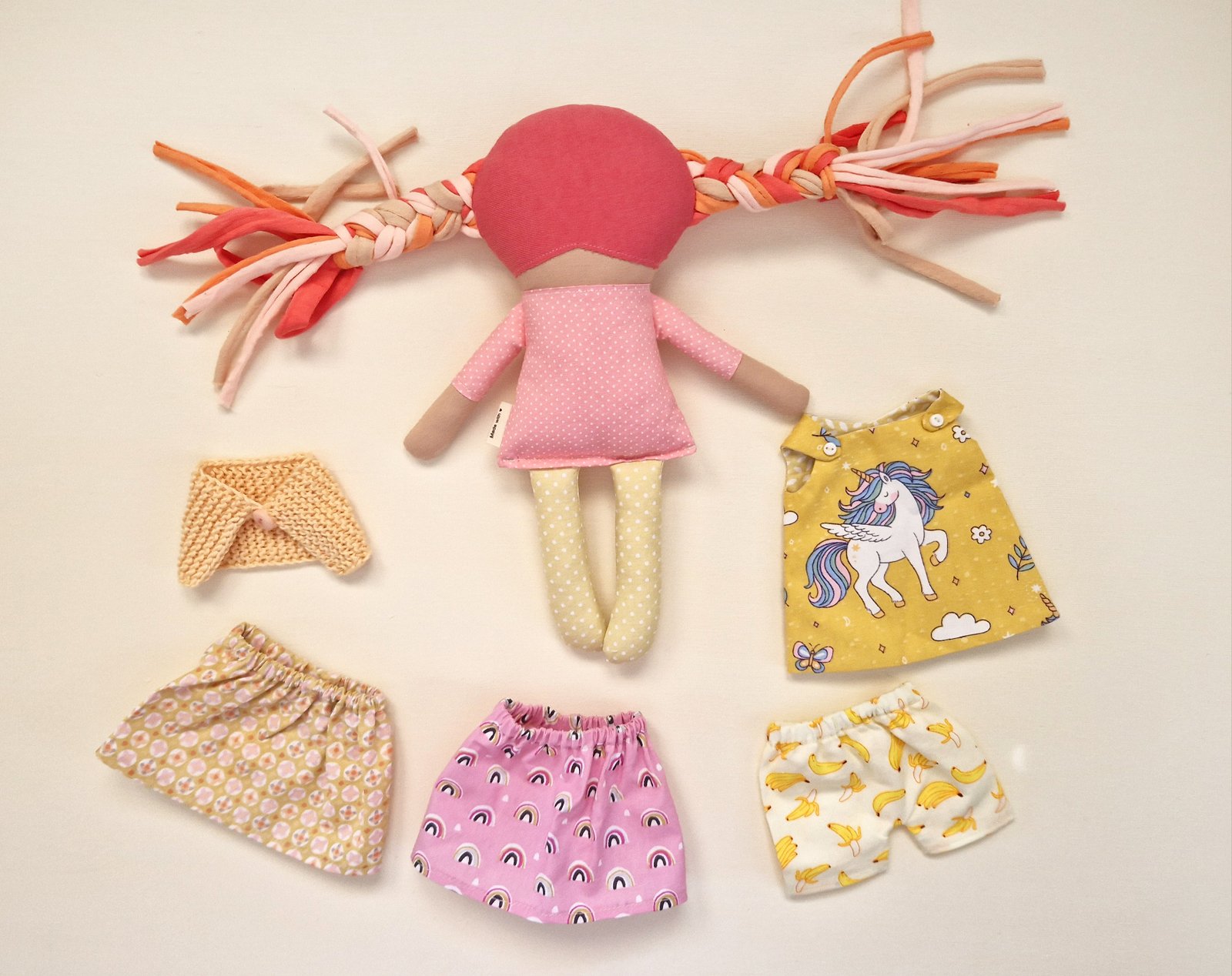 Colorful fabric doll with an interchangeable dress and additional clothing accessories.