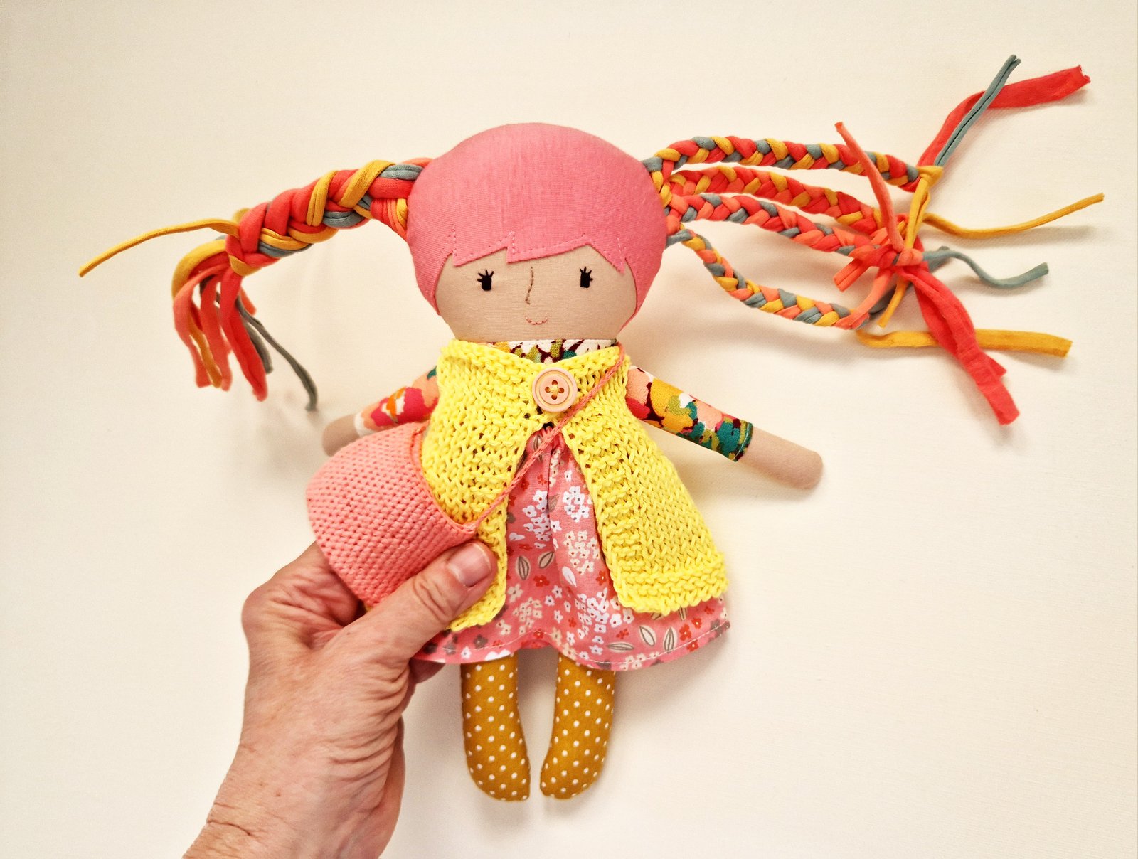 Fabric doll with colorful hair, a floral dress, and additional interchangeable clothes.