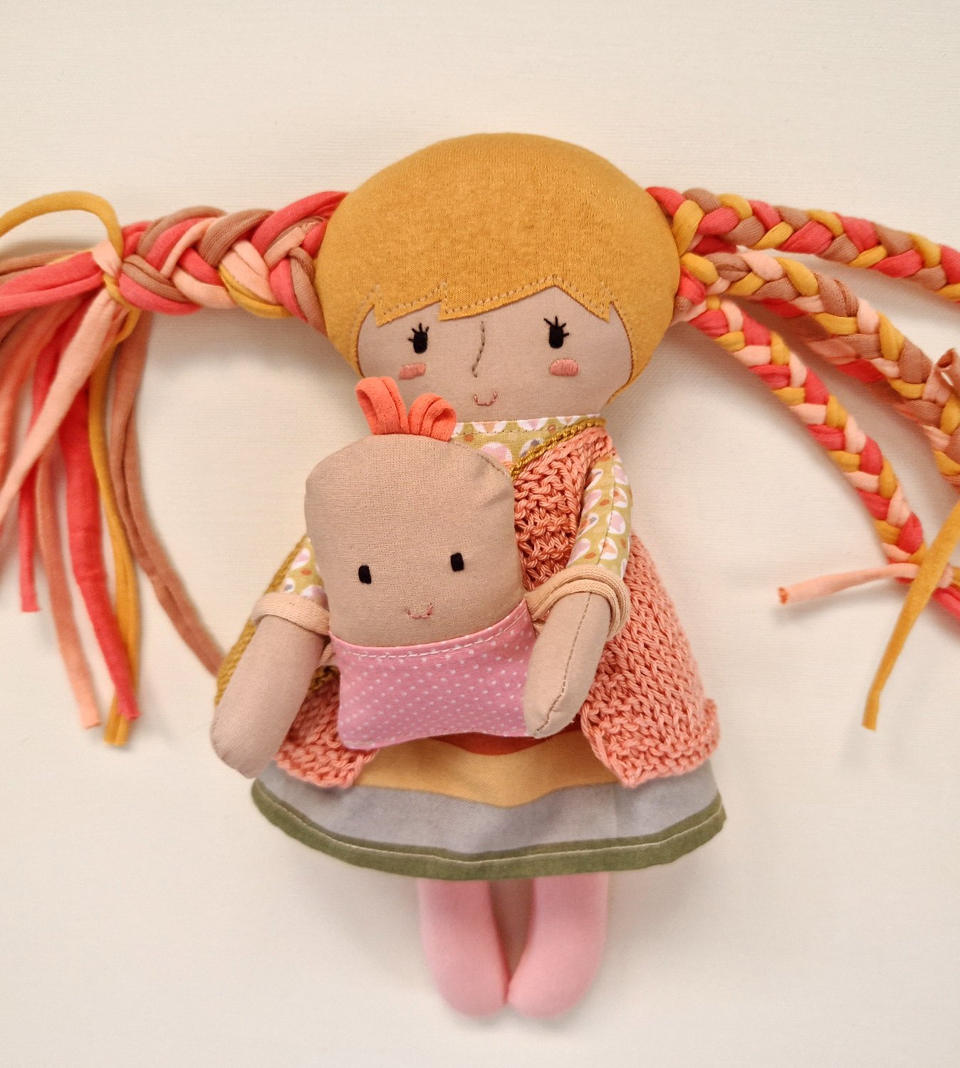 Cloth play doll with long colorful hair and a small baby doll in her arms