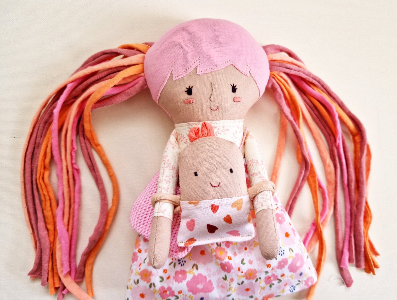 Soft play doll with a floral dress and pink interchangeable doll clothes.