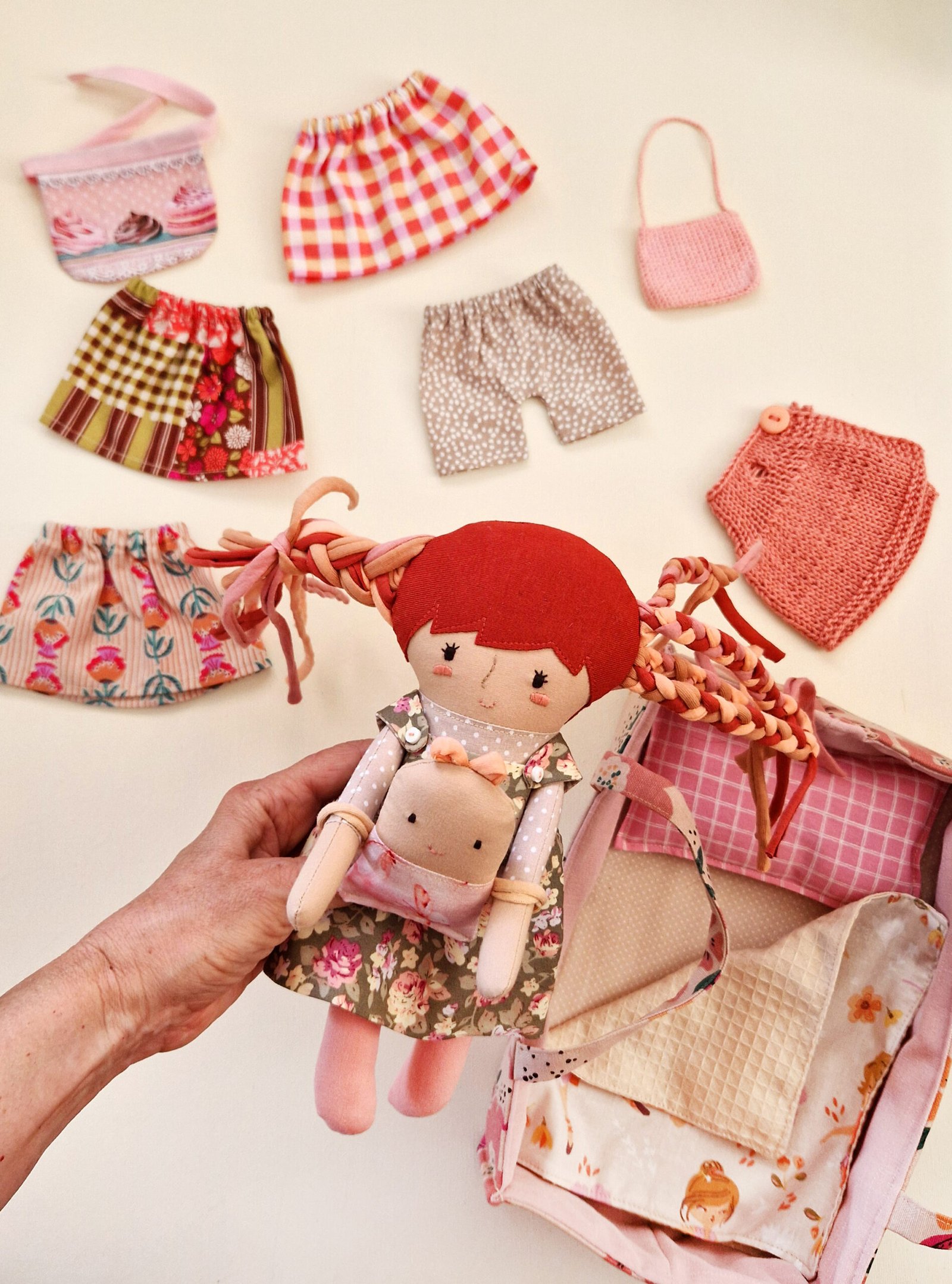 Children's cloth doll with long hair and a selection of skirts and pants.