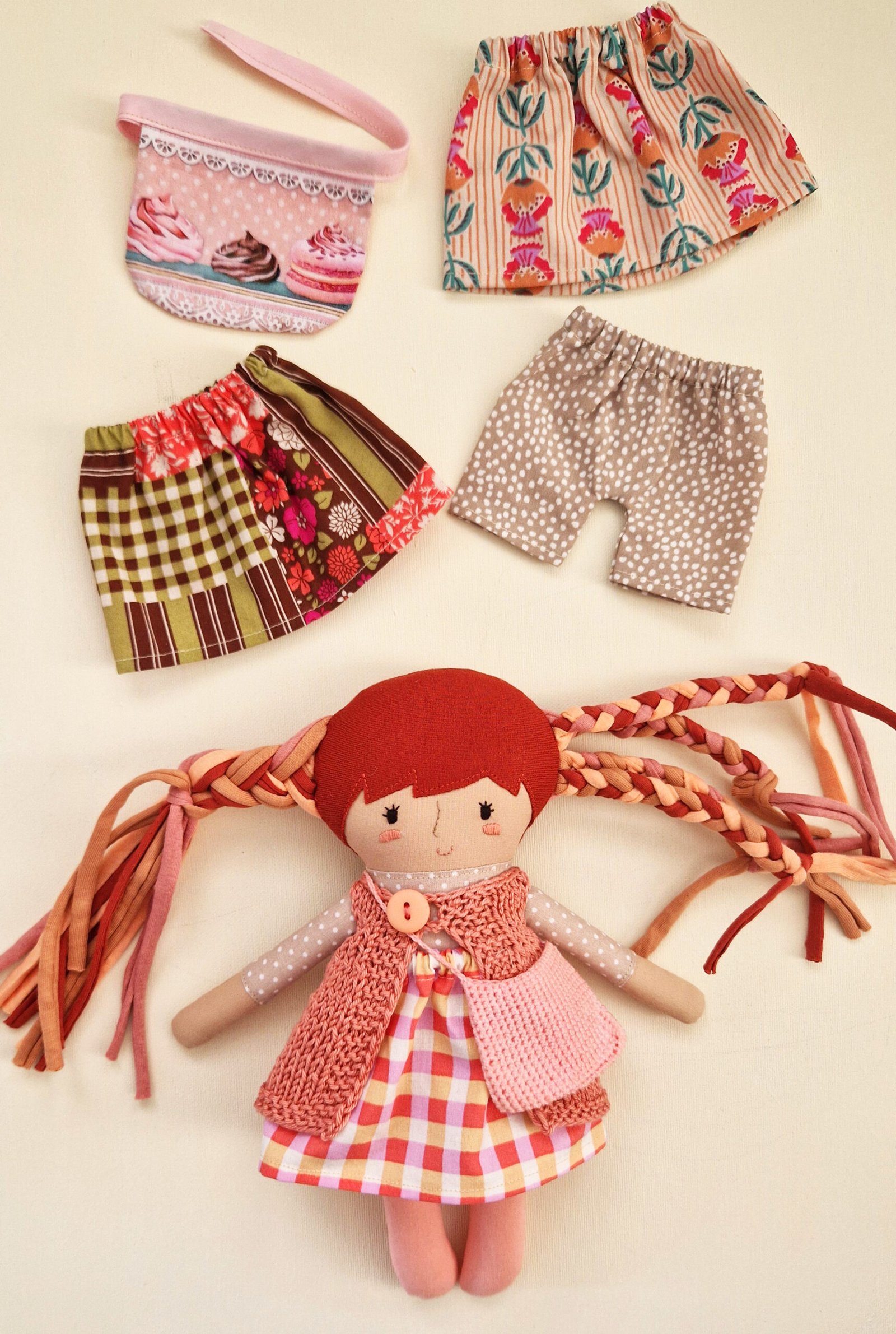 Play doll set with an open fabric bag, interchangeable clothing, and accessories.