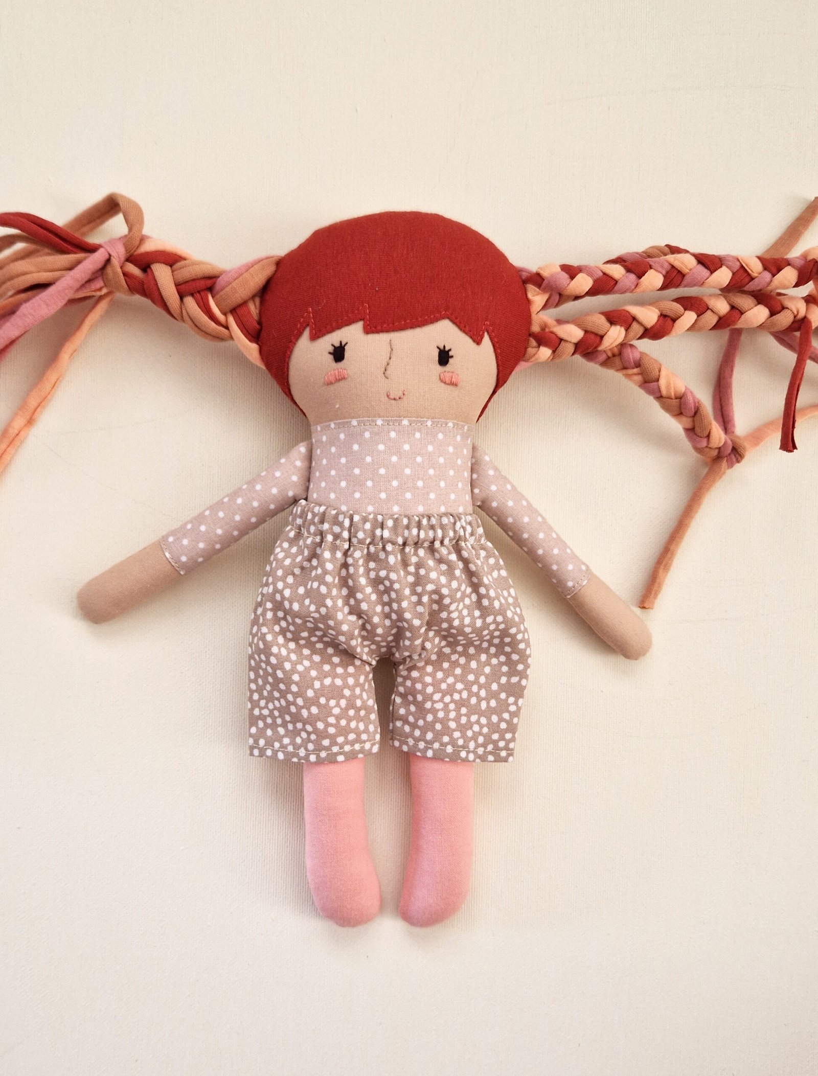 Fabric doll with colorful hair and a stylish collection of miniature outfits.