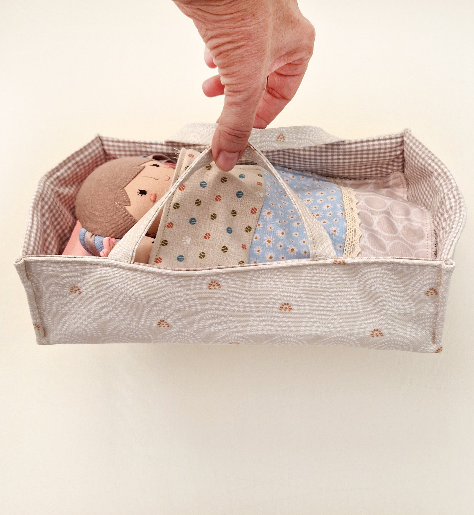 Fabric doll with long pink and blue hair displayed beside a bag and interchangeable clothes.