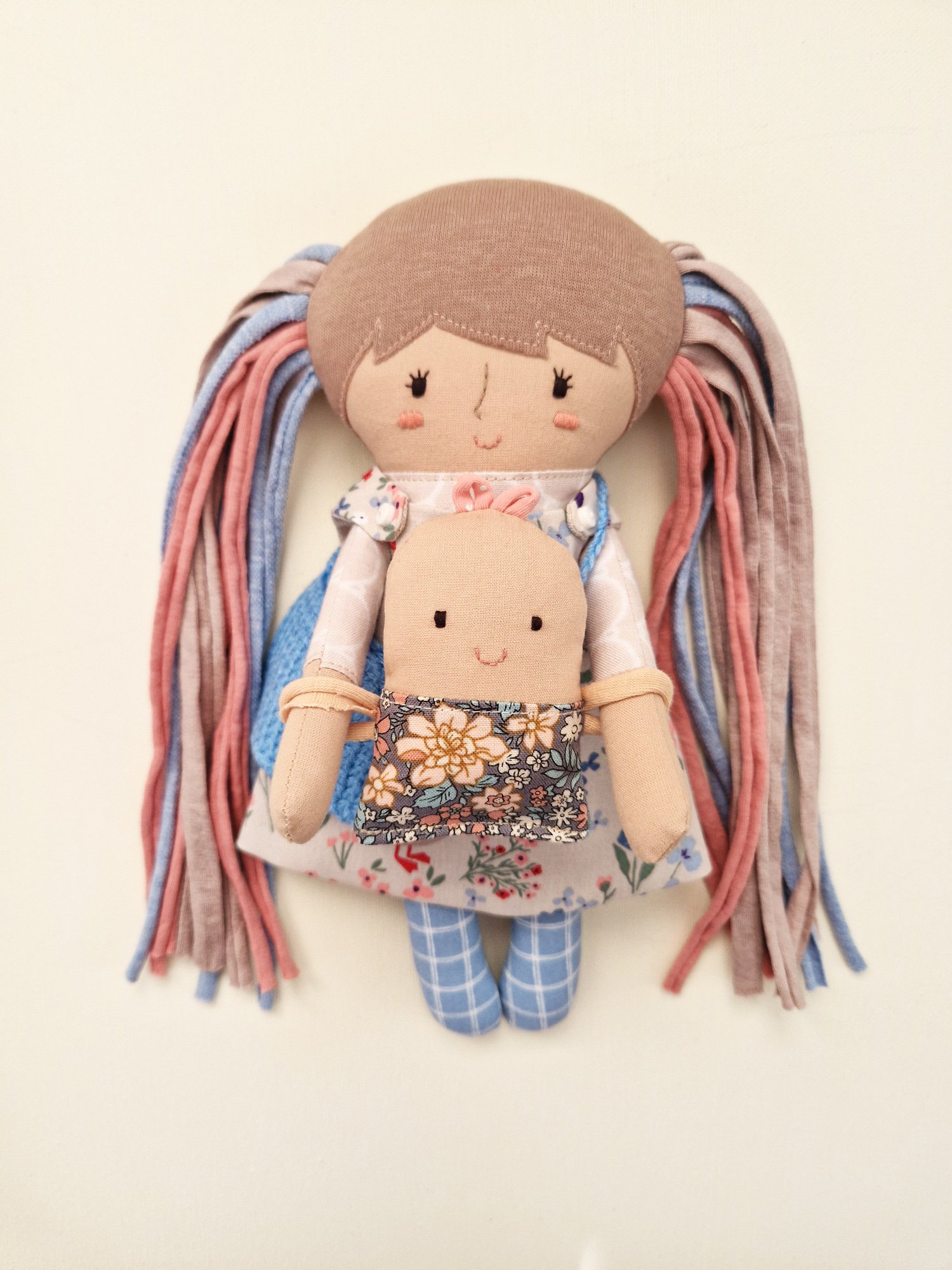 Cloth doll set including a carrying bag, interchangeable outfits, and a small baby doll.