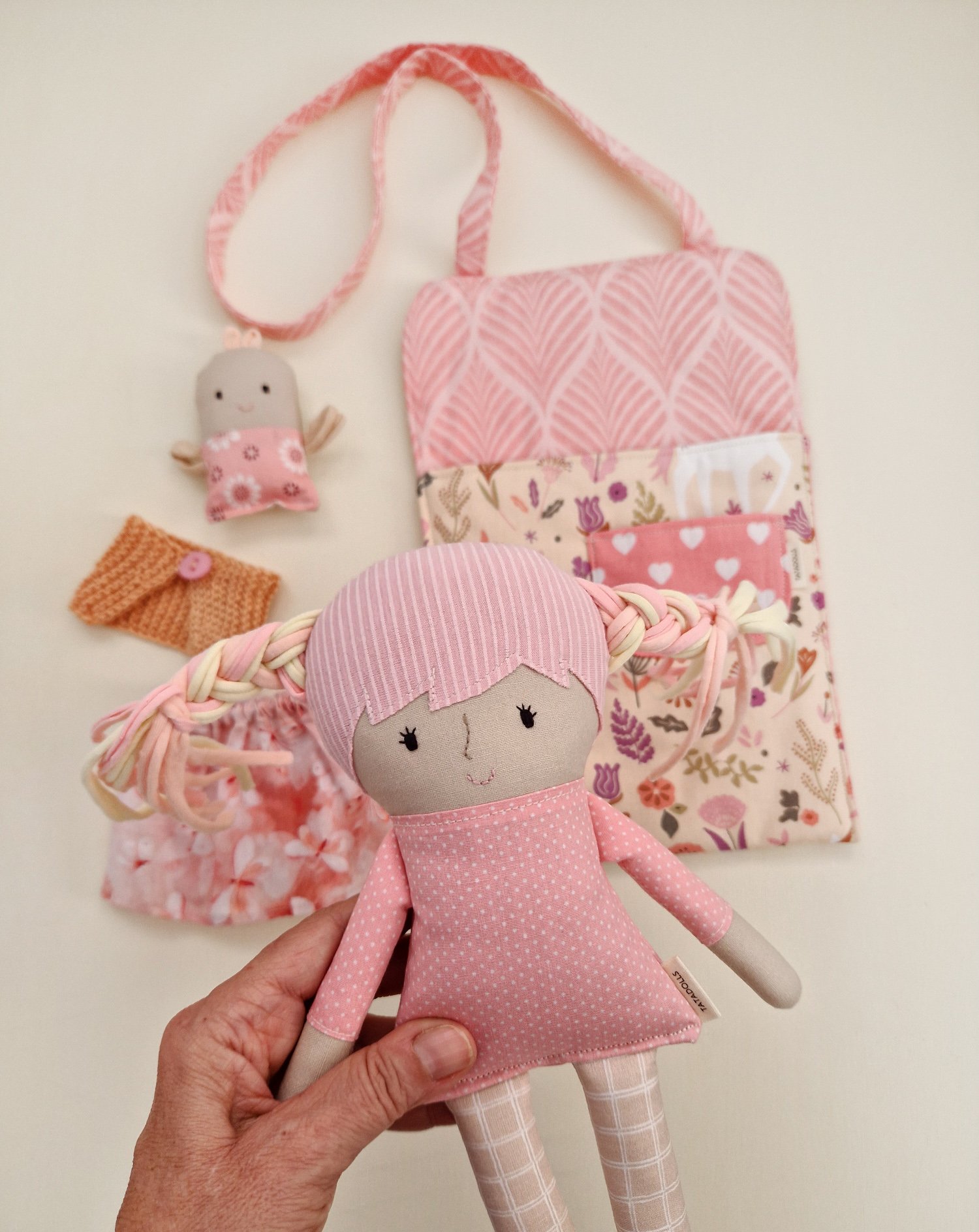 Soft play doll inside a fabric bag with pockets and accessories