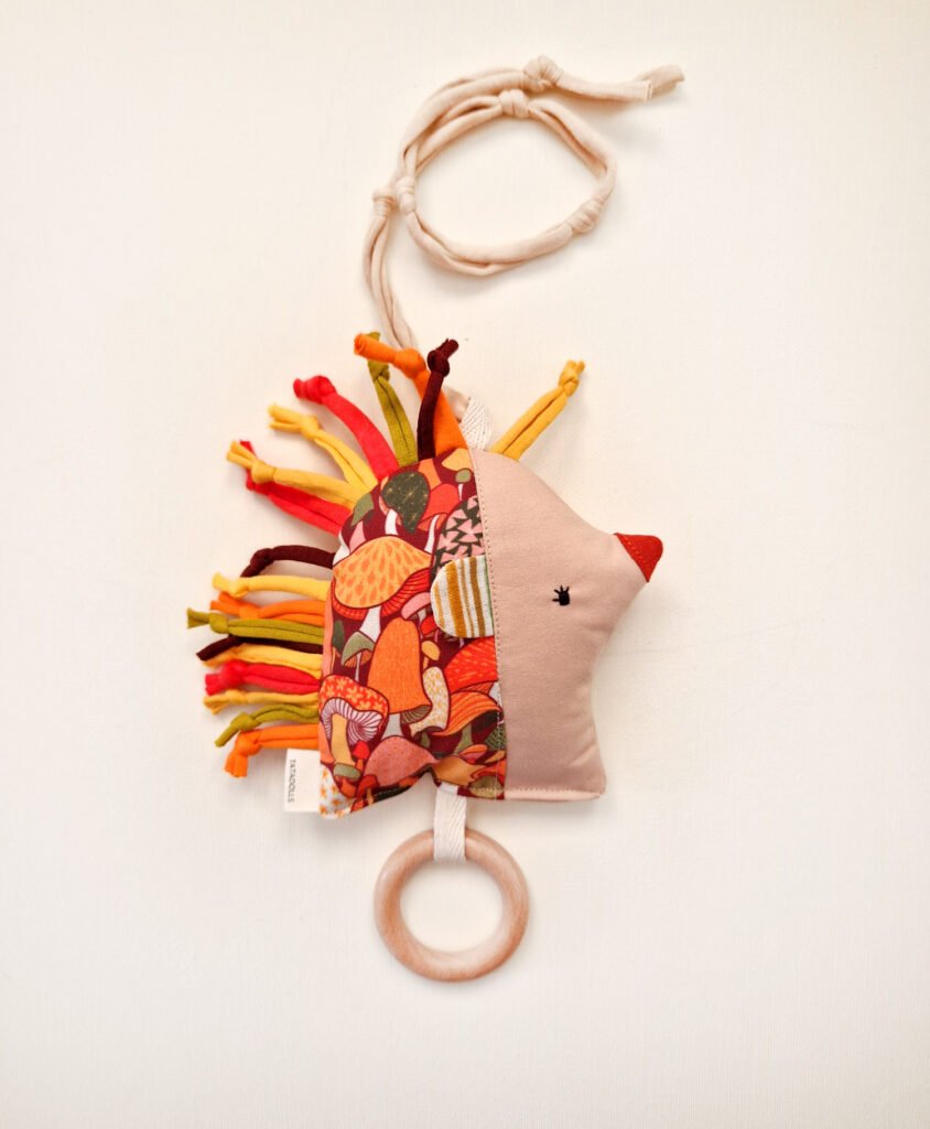 Double-sided fabric hedgehog rattle with colorful floral print and wooden teething ring