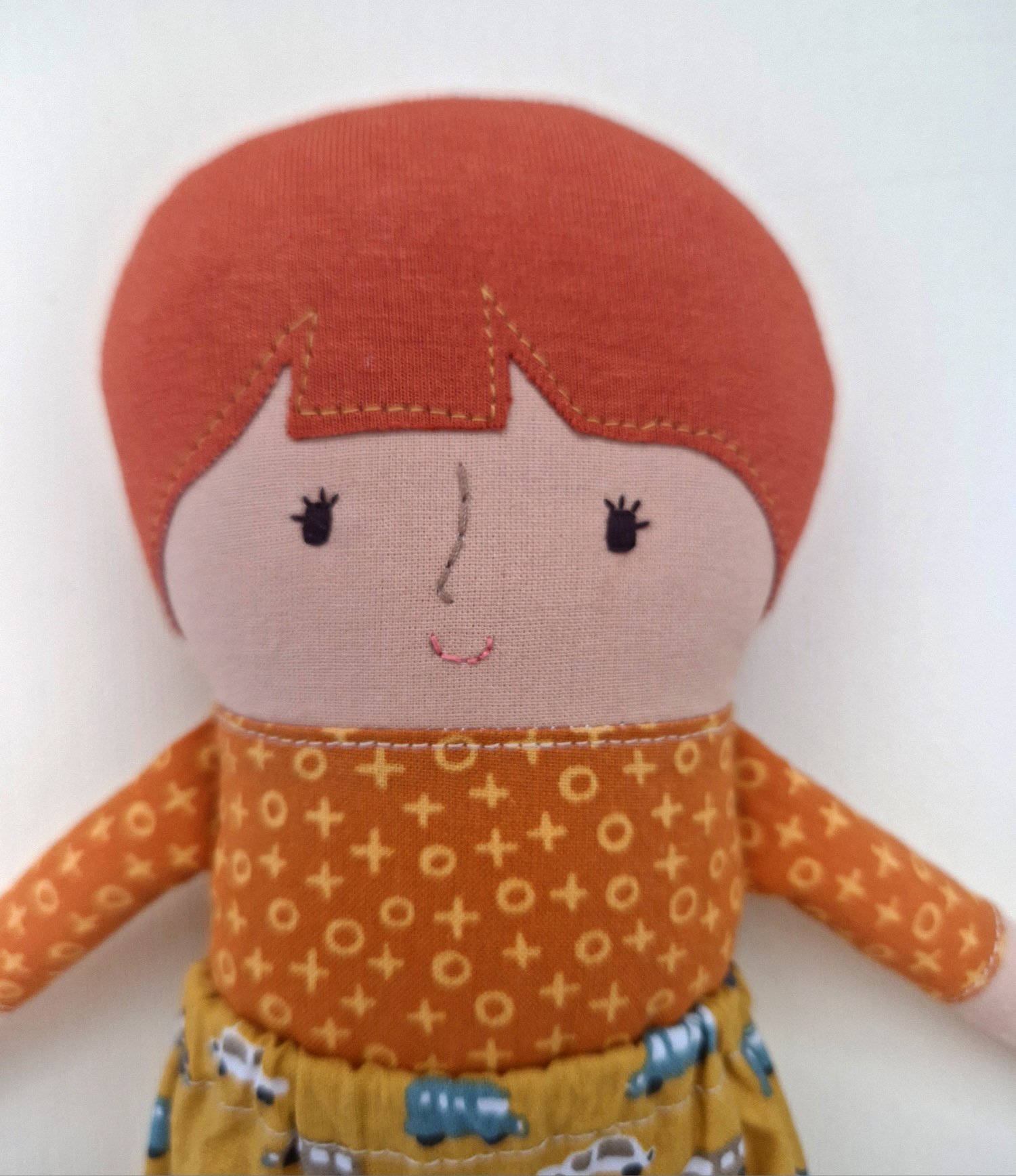 Cute handmade textile doll wearing colorful clothes with cars and buses