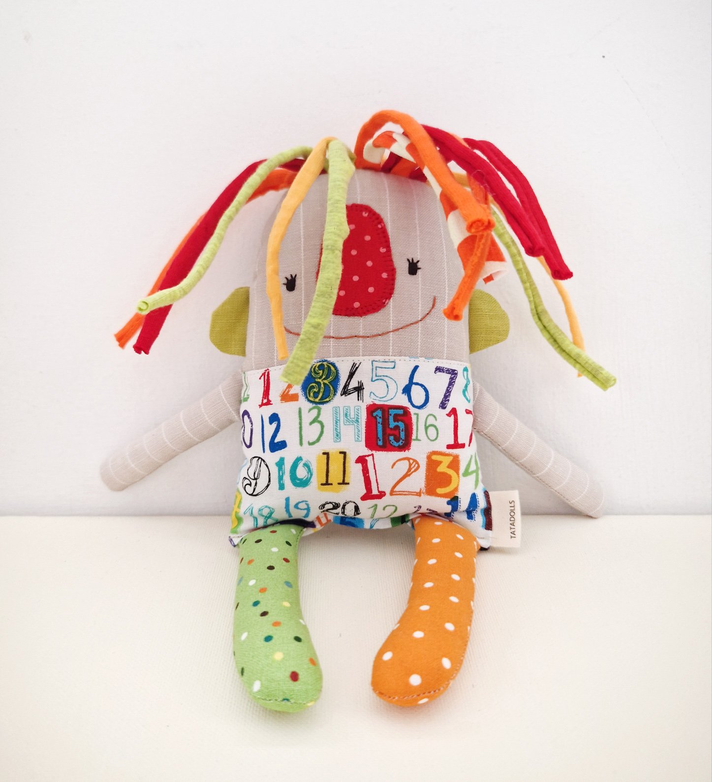 Handmade textile art doll with colorful fabric hair and a skirt printed with numbers
