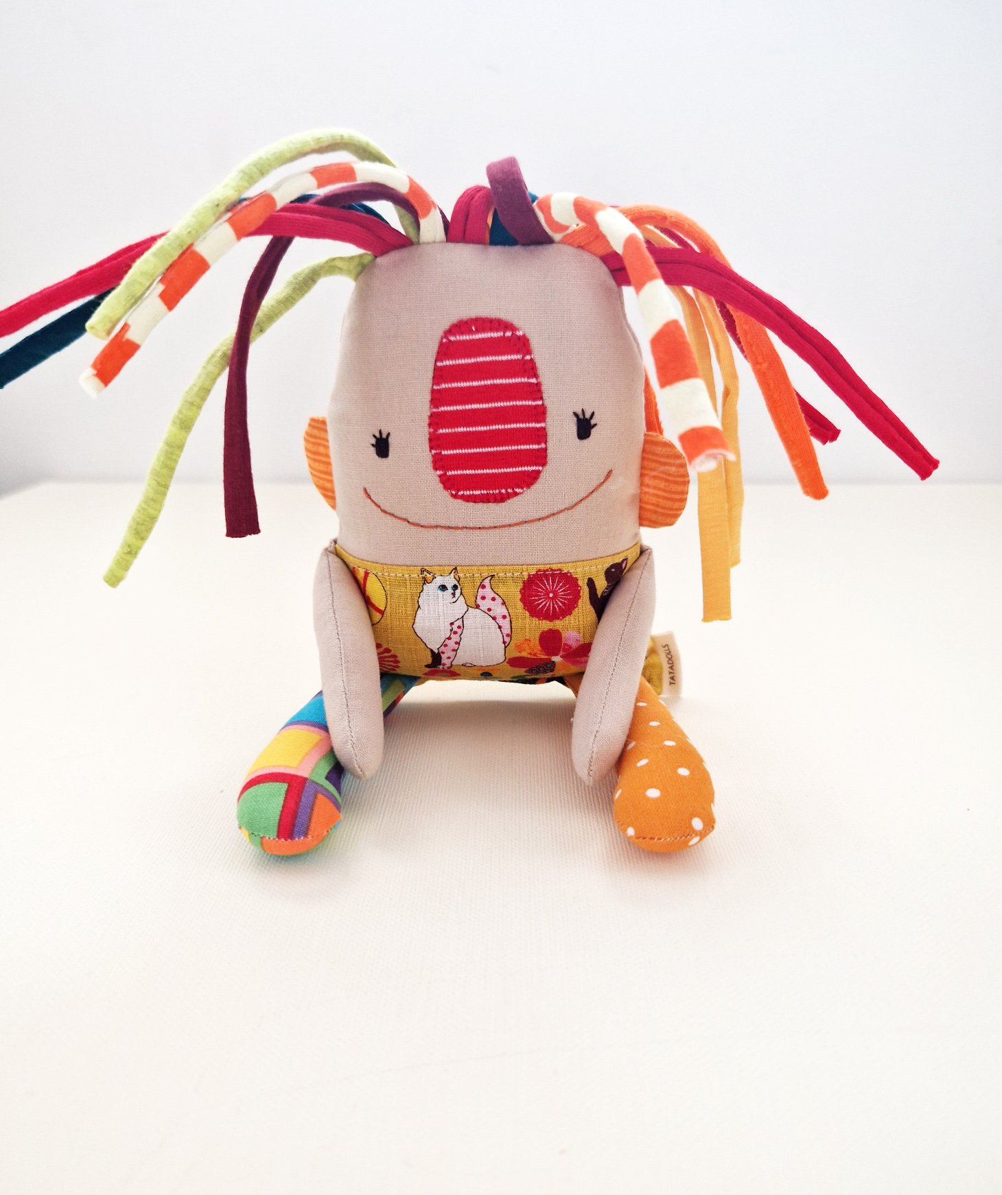 Handmade textile art doll with colorful fabric hair and a yellow skirt with Japanese-inspired illustrations
