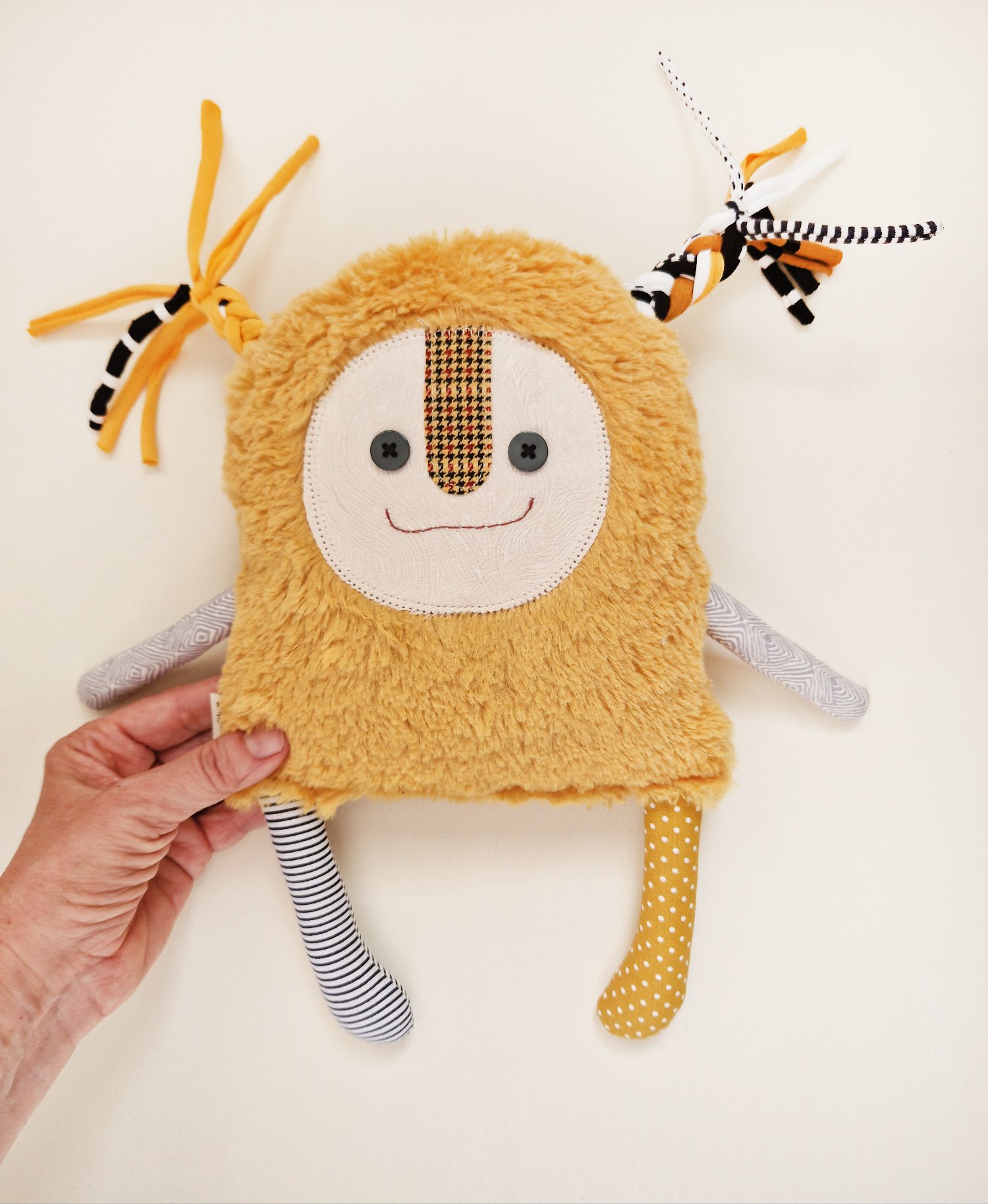 Handmade yellow fluffy fabric doll with colorful ribbon braids and mismatched patterned legs