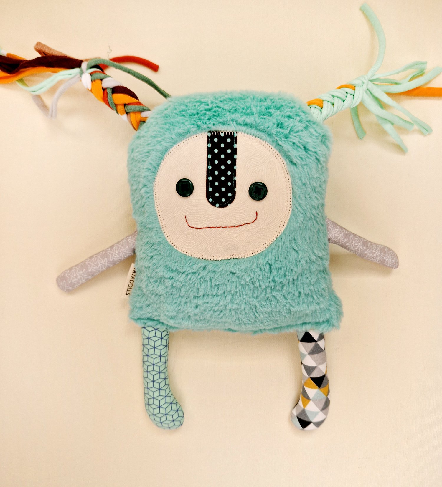Handmade turquoise fluffy fabric doll with colorful ribbon braids and mismatched patterned legs