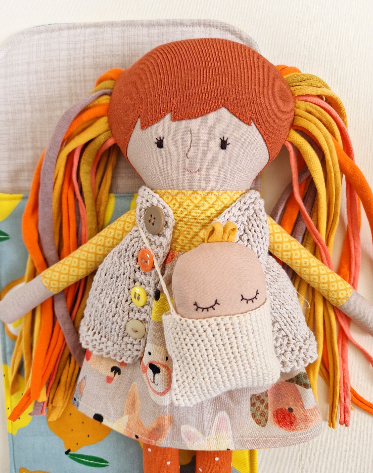 Handmade textile doll with colorful yarn hair sleeping in a citrus print sleeping bag